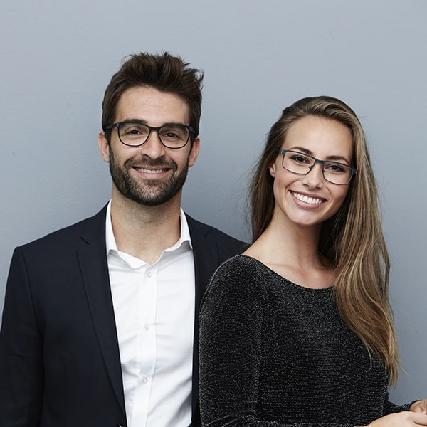 A young couple smiling and wearing glasses