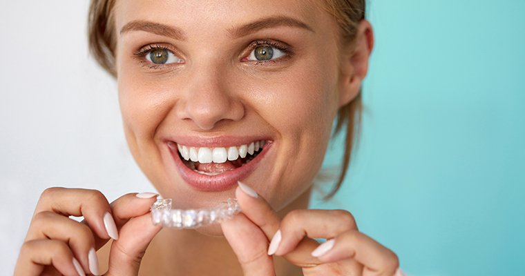 Woman Holding a Clear Aligner for Invisalign Treatment